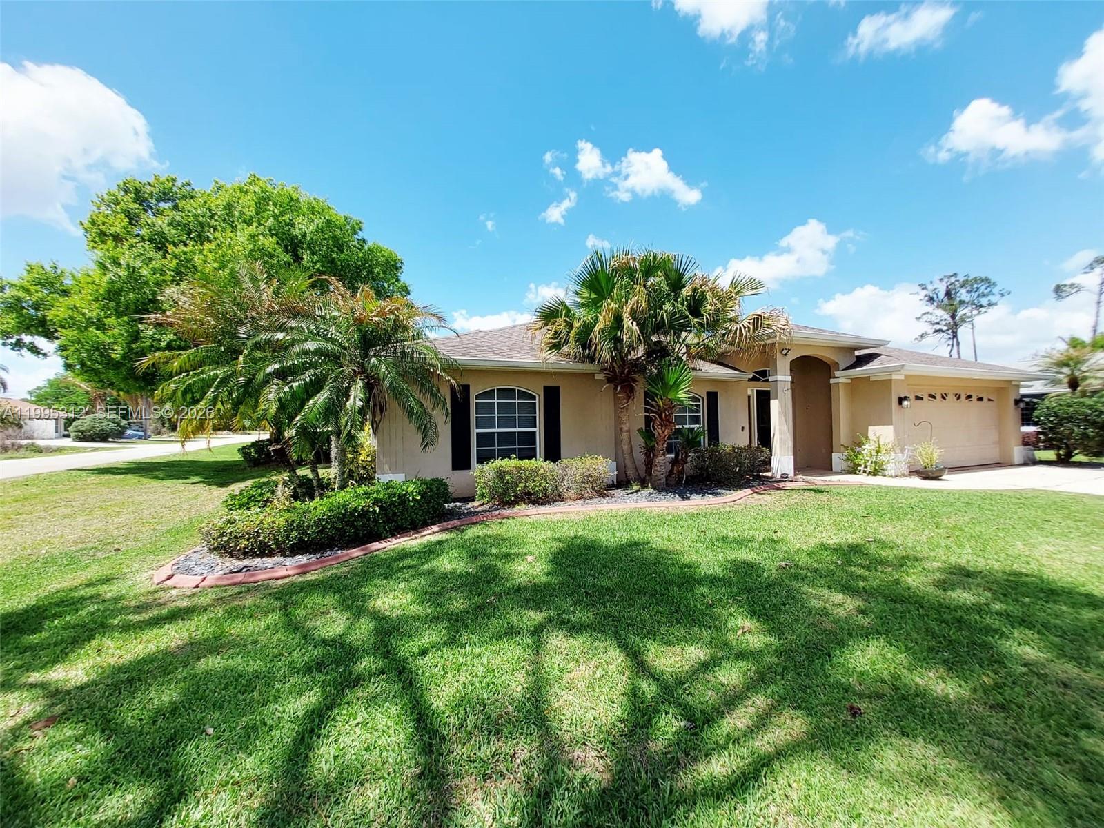 A single-story house with a tan exterior, arched entryway, and palm trees in the front yard — 4031 Santa Barbara, Sebring FL 33875, SEBRING, FL