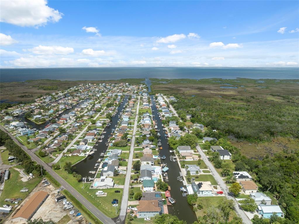 An aerial view shows a residential neighborhood with houses lining canals leading to the ocean — 7711 HATTERAS DRIVE, HUDSON, FL