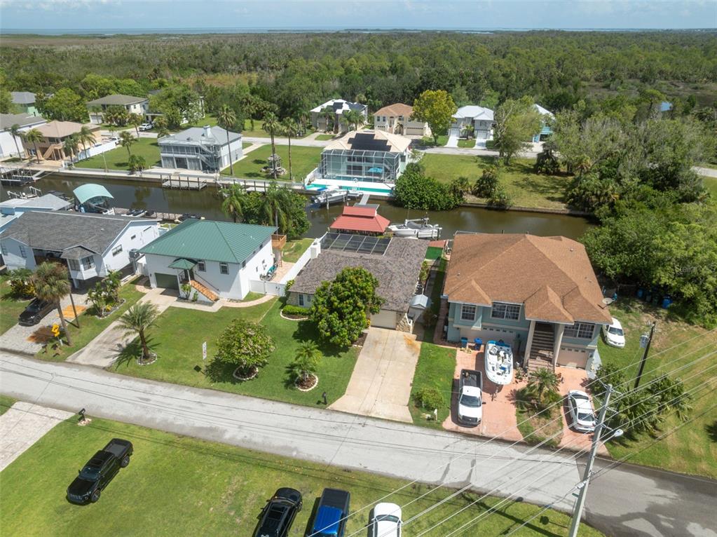 An aerial view shows several waterfront houses with boat docks along a canal — 7711 HATTERAS DRIVE, HUDSON, FL