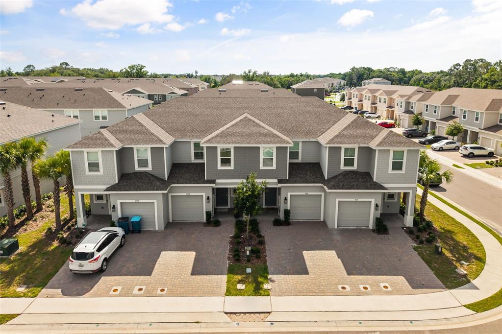 An aerial view shows a multi-unit residential building with gray siding, shingled roofs, and garages — 3002 CANARY AVENUE, DAVENPORT, FL