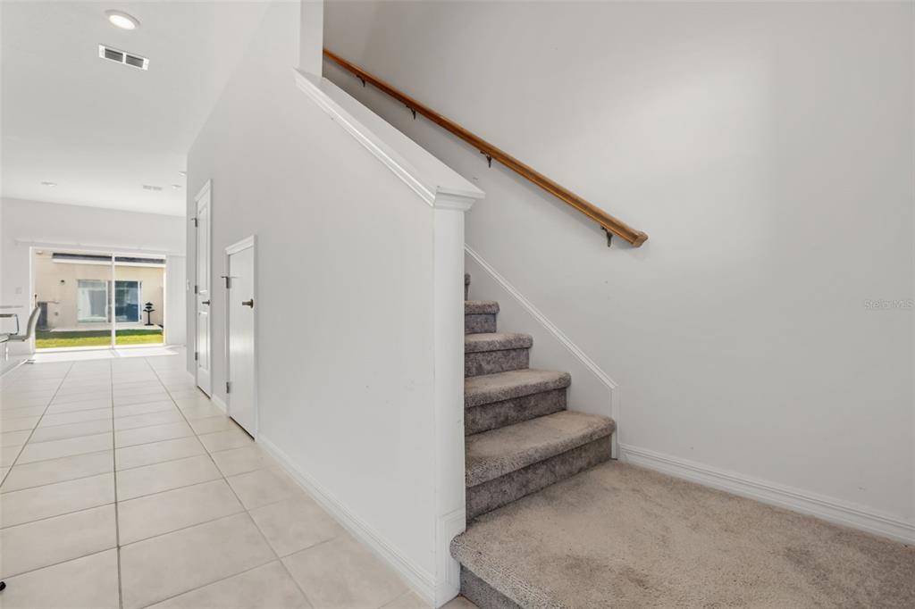 A carpeted staircase with a wooden handrail sits next to a tiled hallway — 3002 CANARY AVENUE, DAVENPORT, FL