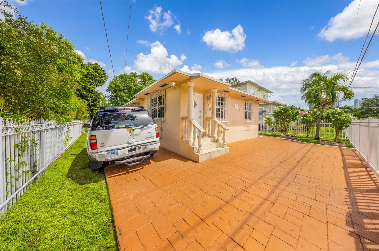 A light-colored single-story house features a paved driveway and a white fence under a sky — 287 NW 31st St, Miami FL 33127, MIAMI, FL