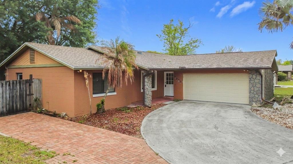 A single-story house with a brick driveway, two-car garage, and stone accents on the exterior — 5503 ALBERT DRIVE, WINTER PARK, FL