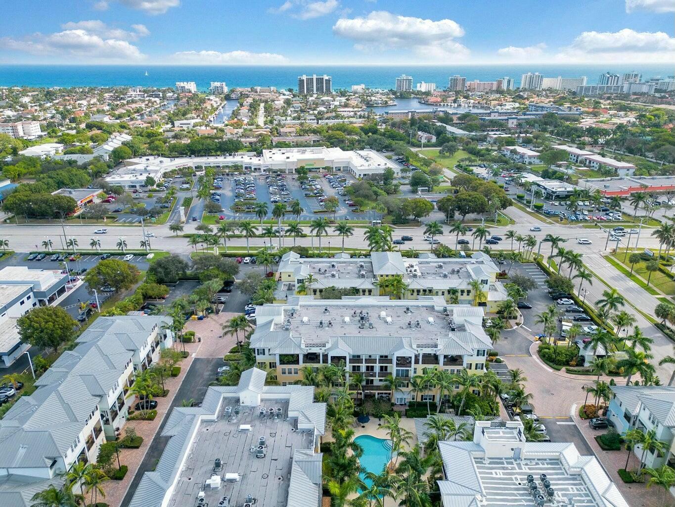 An aerial view shows a multi-story residential complex with a pool near a coastal town — 3120 E Latitude Circle # 206, Delray Beach FL 33483, DELRAY BEACH, FL