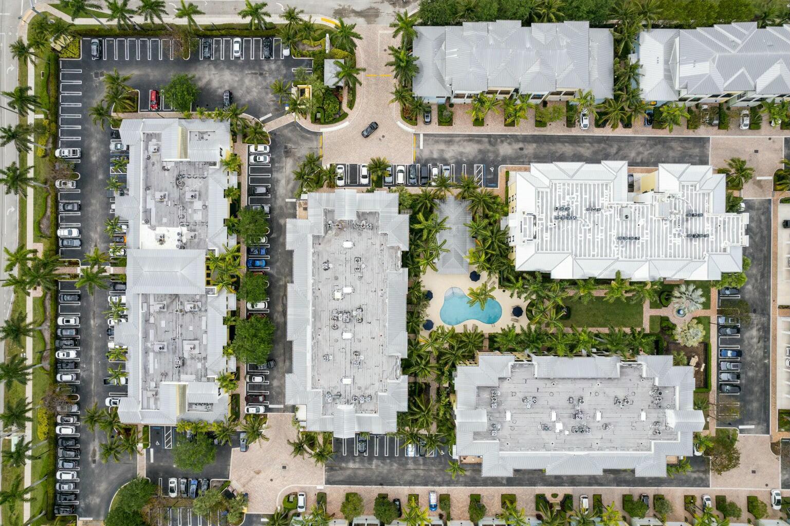 Aerial view of a residential apartment complex with a central swimming pool and parking lots — 3120 E Latitude Circle # 206, Delray Beach FL 33483, DELRAY BEACH, FL