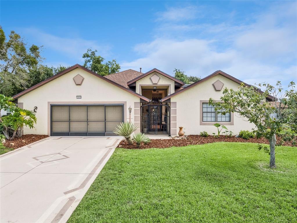 A single-story house with a beige stucco exterior, a two-car garage, and a gated entryway — 21815 TARTAN STREET, LEESBURG, FL