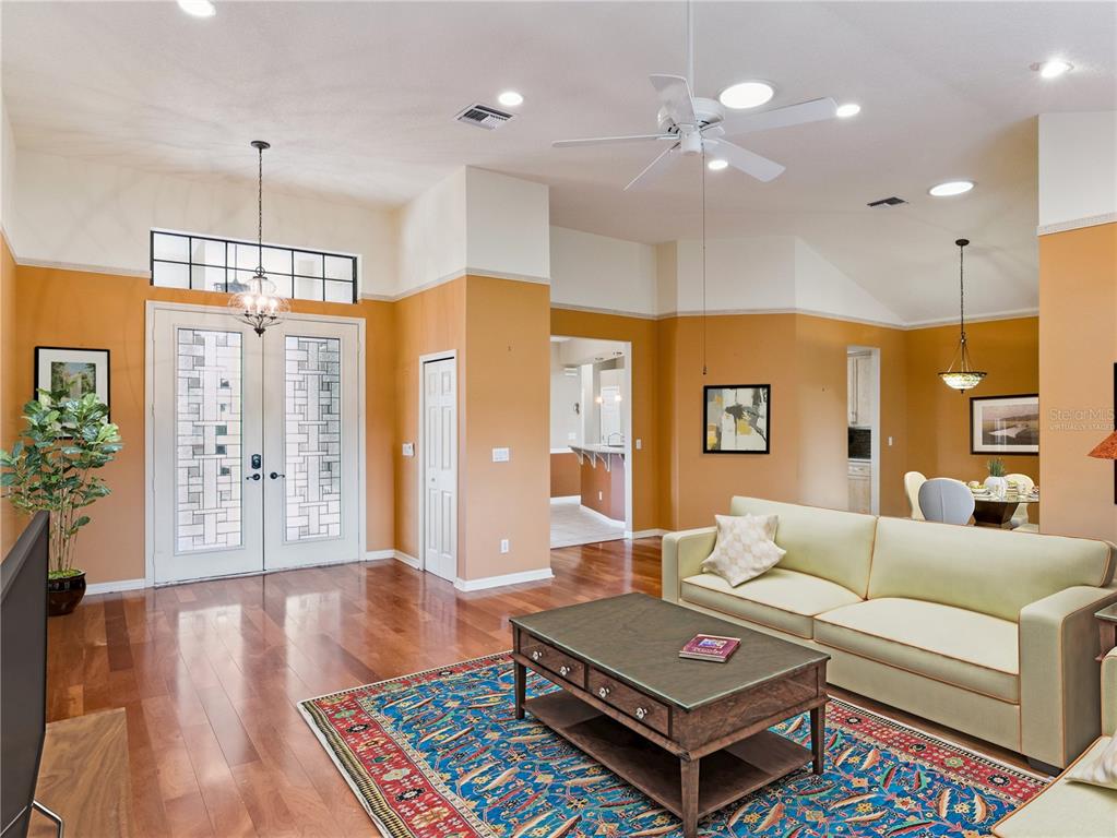 A living room features hardwood floors, a patterned rug, a light-colored sofa, and orange walls — 21815 TARTAN STREET, LEESBURG, FL