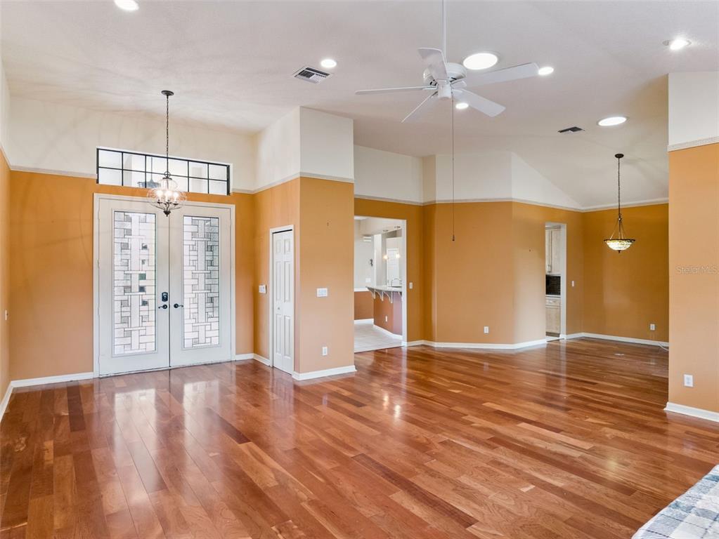 An entryway with hardwood floors, orange walls, a double front door, and a ceiling fan — 21815 TARTAN STREET, LEESBURG, FL