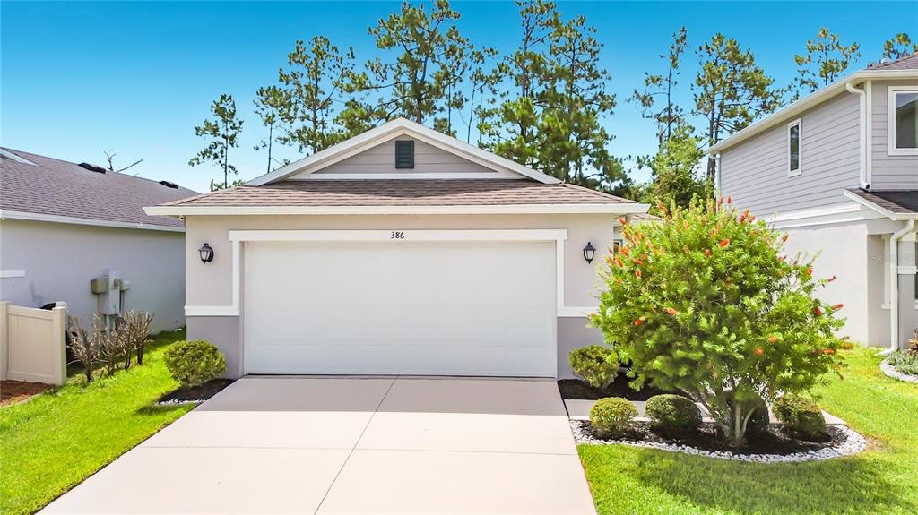 A single-story house with a two-car garage, light gray siding, and a landscaped front yard — 386 PRESERVE POINTE BOULEVARD, DAVENPORT, FL