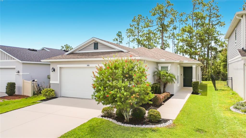 A single-story house with a two-car garage, a front lawn, and a paved walkway — 386 PRESERVE POINTE BOULEVARD, DAVENPORT, FL