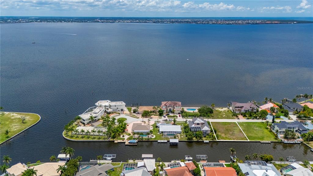 An aerial view shows a vacant waterfront lot situated among residential homes along a canal — 238 GEORGE ROAD SE, PORT CHARLOTTE, FL