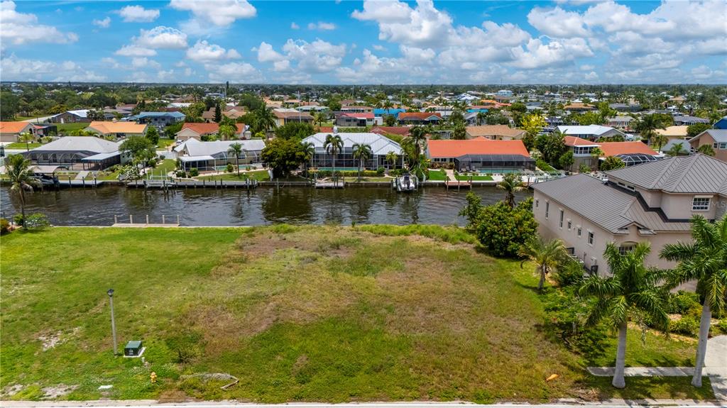An aerial view shows a vacant waterfront lot with a canal and neighboring houses — 238 GEORGE ROAD SE, PORT CHARLOTTE, FL