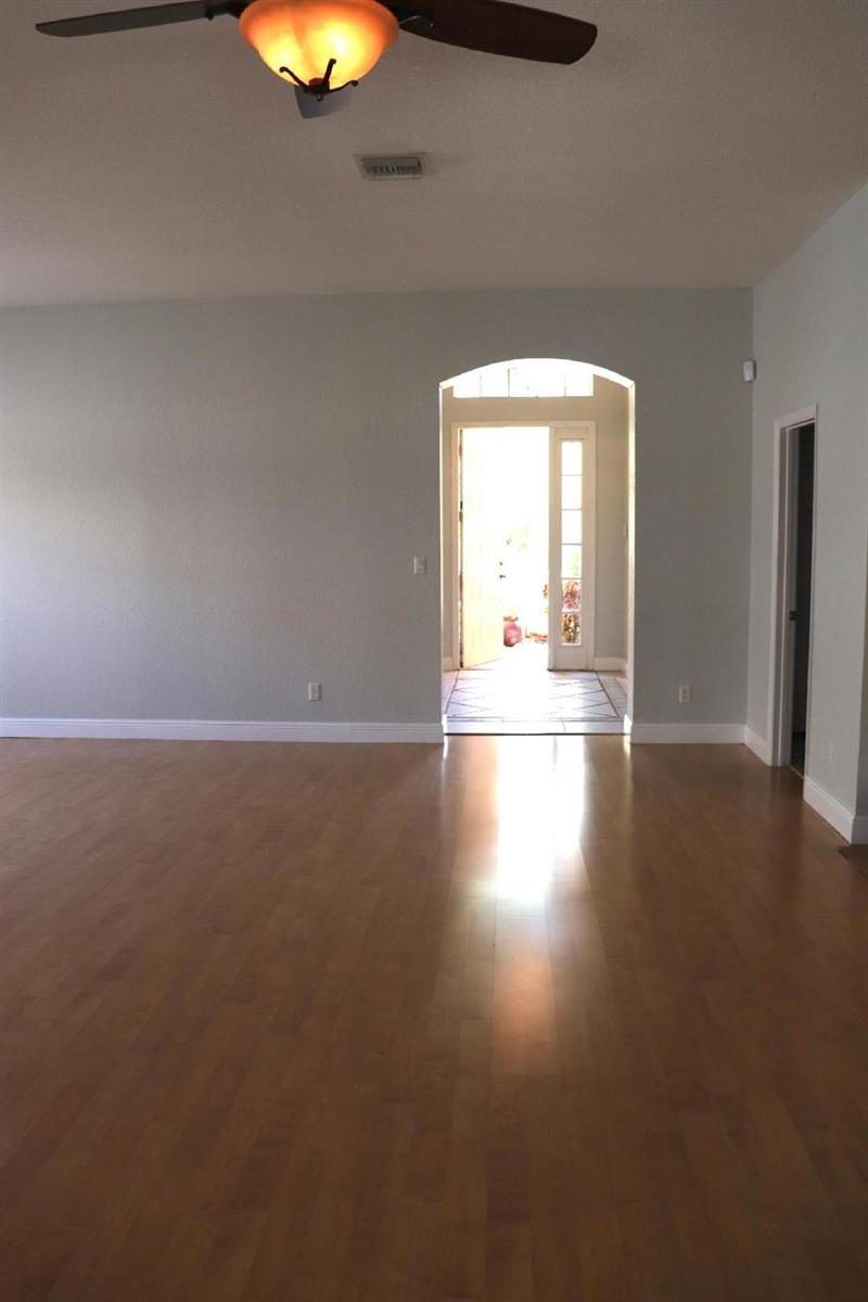 An empty room with light-colored walls, hardwood floors, a ceiling fan, and an arched entryway — 19298 Seneca Avenue, Weston FL 33332, WESTON, FL