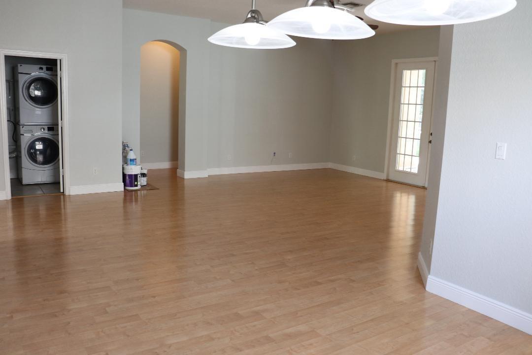 An open dining area features light wood flooring, pendant lighting, and a stacked laundry unit — 19298 Seneca Avenue, Weston FL 33332, WESTON, FL