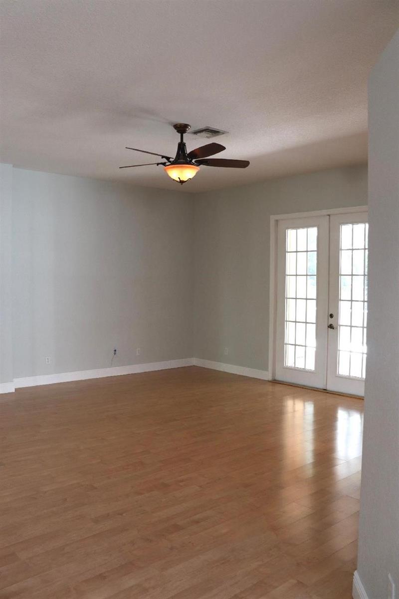 An empty room features light wood flooring, pale gray walls, a ceiling fan, and French doors — 19298 Seneca Avenue, Weston FL 33332, WESTON, FL