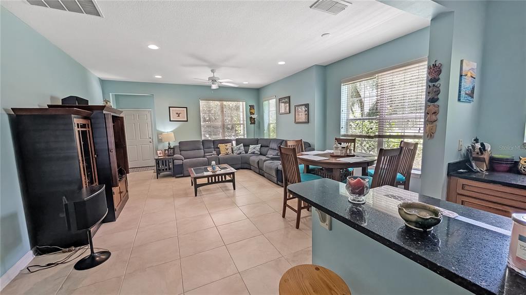 An open-concept living and dining area features tile flooring, a sectional sofa, and kitchen counters — 1114 TAPESTRY DRIVE, CELEBRATION, FL