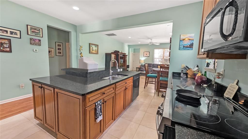A kitchen features wood cabinets, dark granite countertops, a central island, and light-colored walls — 1114 TAPESTRY DRIVE, CELEBRATION, FL