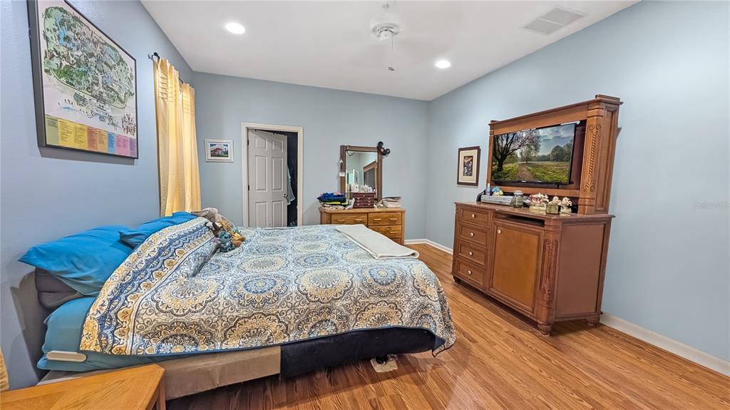 A bedroom features light blue walls, wood flooring, a patterned bedspread, and a wooden dresser — 1114 TAPESTRY DRIVE, CELEBRATION, FL