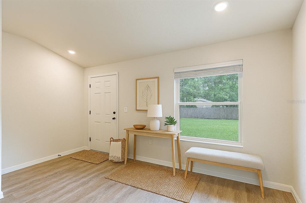 An entryway features light wood flooring, a white door, a console table, and a window bench — 111 E HARVARD STREET, INVERNESS, FL
