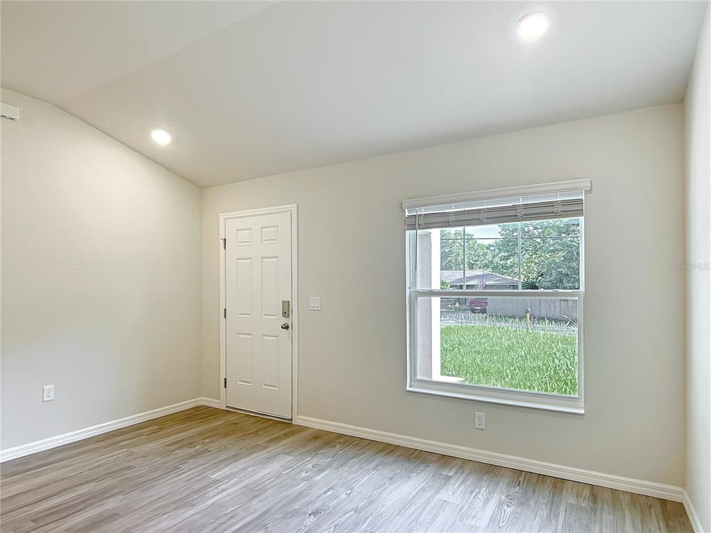 An empty room with light-colored walls, wood-look flooring, a white door, and a single window — 111 E HARVARD STREET, INVERNESS, FL