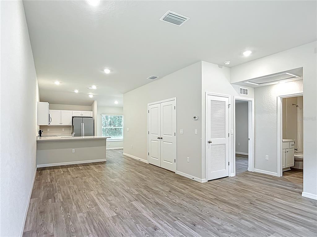 An open-concept living area features wood-look flooring, a kitchen with white cabinets, and white doors — 111 E HARVARD STREET, INVERNESS, FL