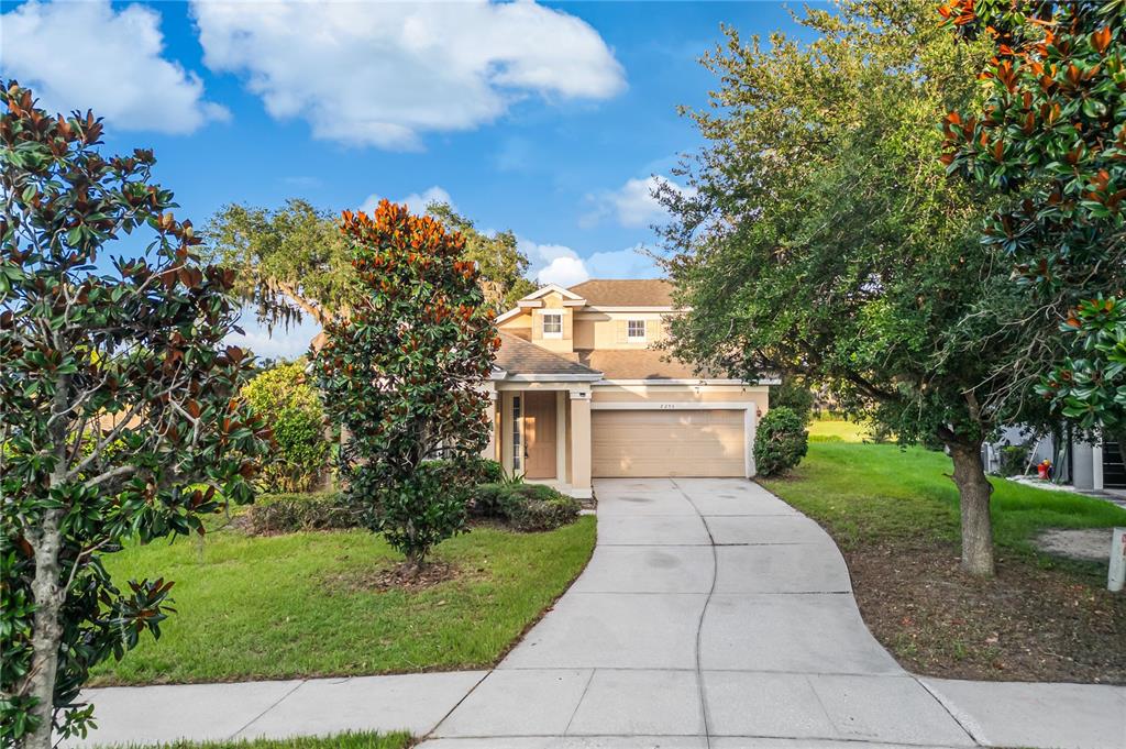 A two-story house with a beige exterior, a two-car garage, and a concrete driveway — 2205 GRANGER AVENUE, KISSIMMEE, FL
