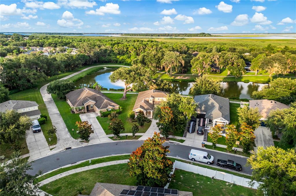 An aerial view shows suburban houses with driveways and a pond near a wooded area — 2205 GRANGER AVENUE, KISSIMMEE, FL