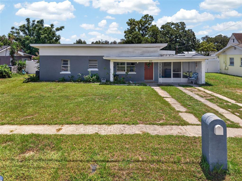A single-story gray house with a flat roof, a front porch, and a concrete driveway — 215 PALM AVENUE, AUBURNDALE, FL