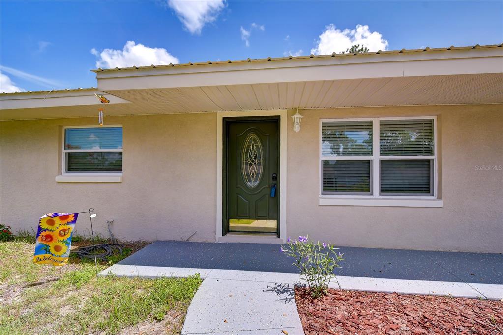 The exterior of a house features a green front door, a concrete porch, and windows — 3423 PALM ROAD, LAKELAND, FL