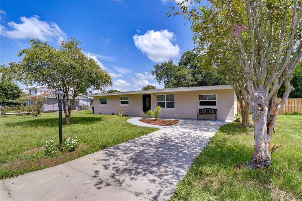 A single-story house with a beige exterior, a concrete walkway, and trees in the yard — 3423 PALM ROAD, LAKELAND, FL