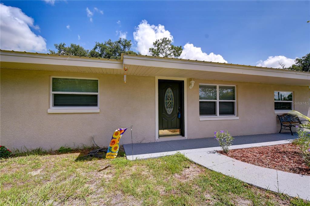 A single-story house exterior features a beige stucco facade, a dark front door, and windows — 3423 PALM ROAD, LAKELAND, FL