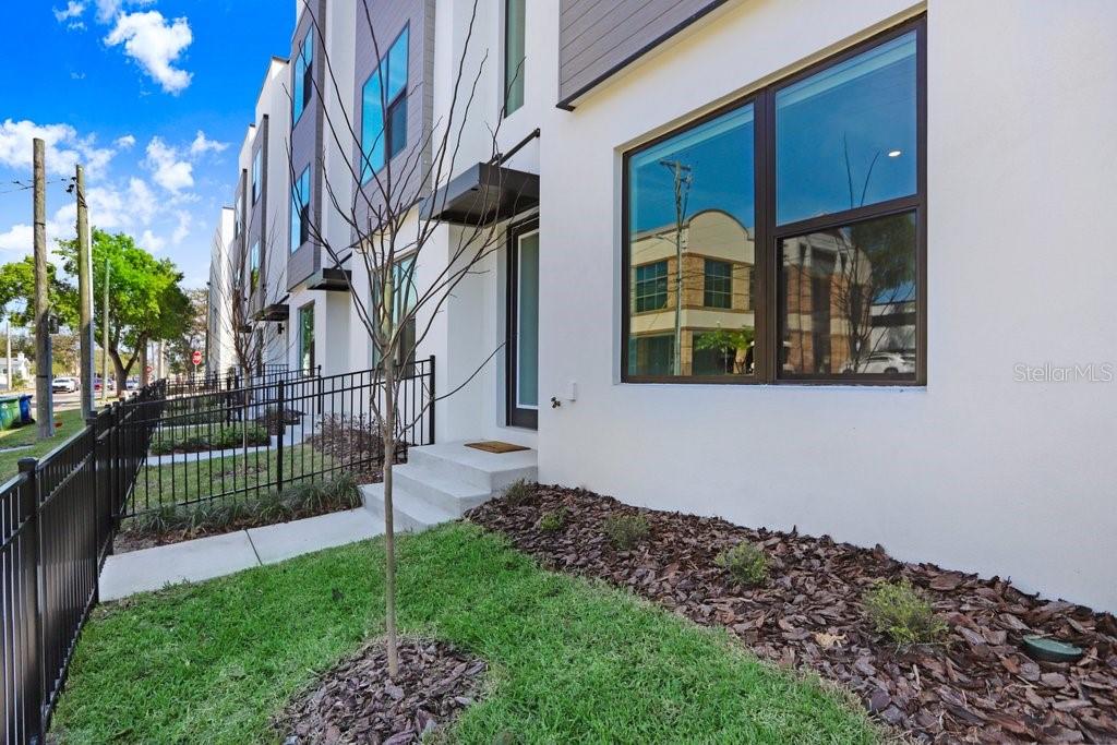 A modern white townhouse exterior features a black metal fence, small front steps, and landscaping — 2506 W CLEVELAND STREET UNIT 20, TAMPA, FL