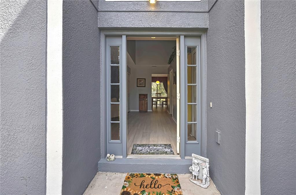 A front entryway with a gray door, sidelights, and a welcome mat leading into a home — 11257 PERSIMMON AVENUE, WEEKI WACHEE, FL