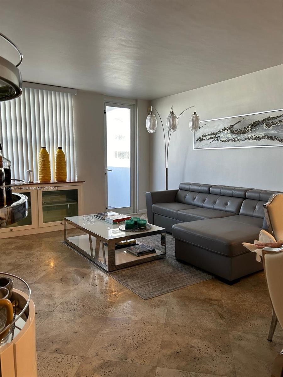 A living room features a grey sectional sofa, a glass coffee table, and tile flooring — 100 Lincoln Rd # 608, Miami Beach FL 33139, MIAMI BEACH, FL
