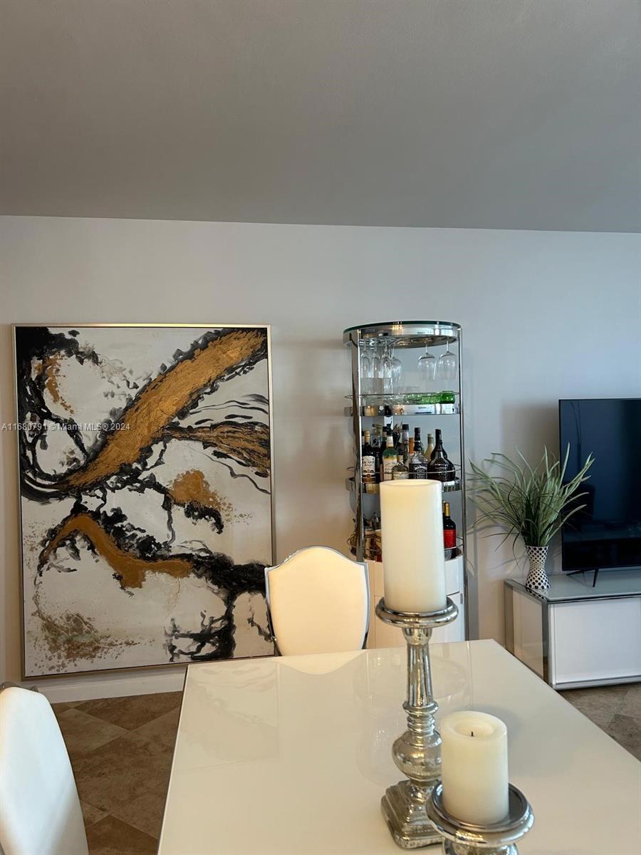 A dining room features a white table, a tall bar cart, and abstract wall art — 100 Lincoln Rd # 608, Miami Beach FL 33139, MIAMI BEACH, FL