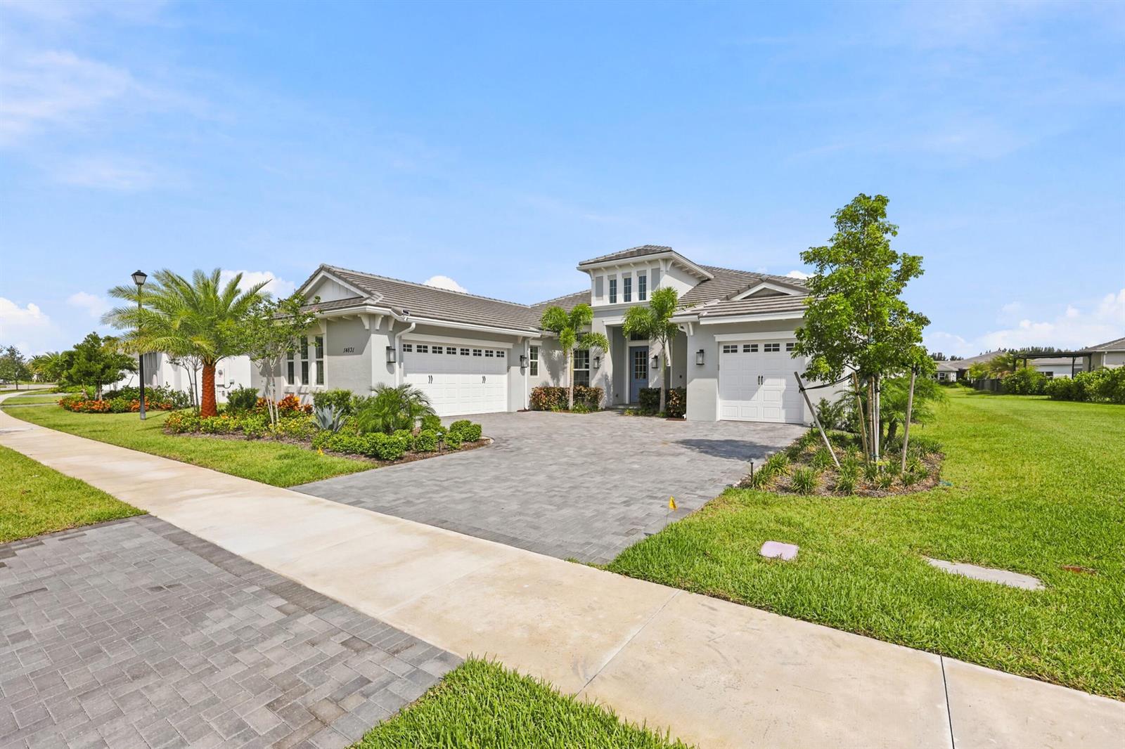 A single-story house with a gray tiled roof, two garage doors, and a paved driveway — 14831 Wildwood Circle, Westlake FL 33470, WESTLAKE, FL