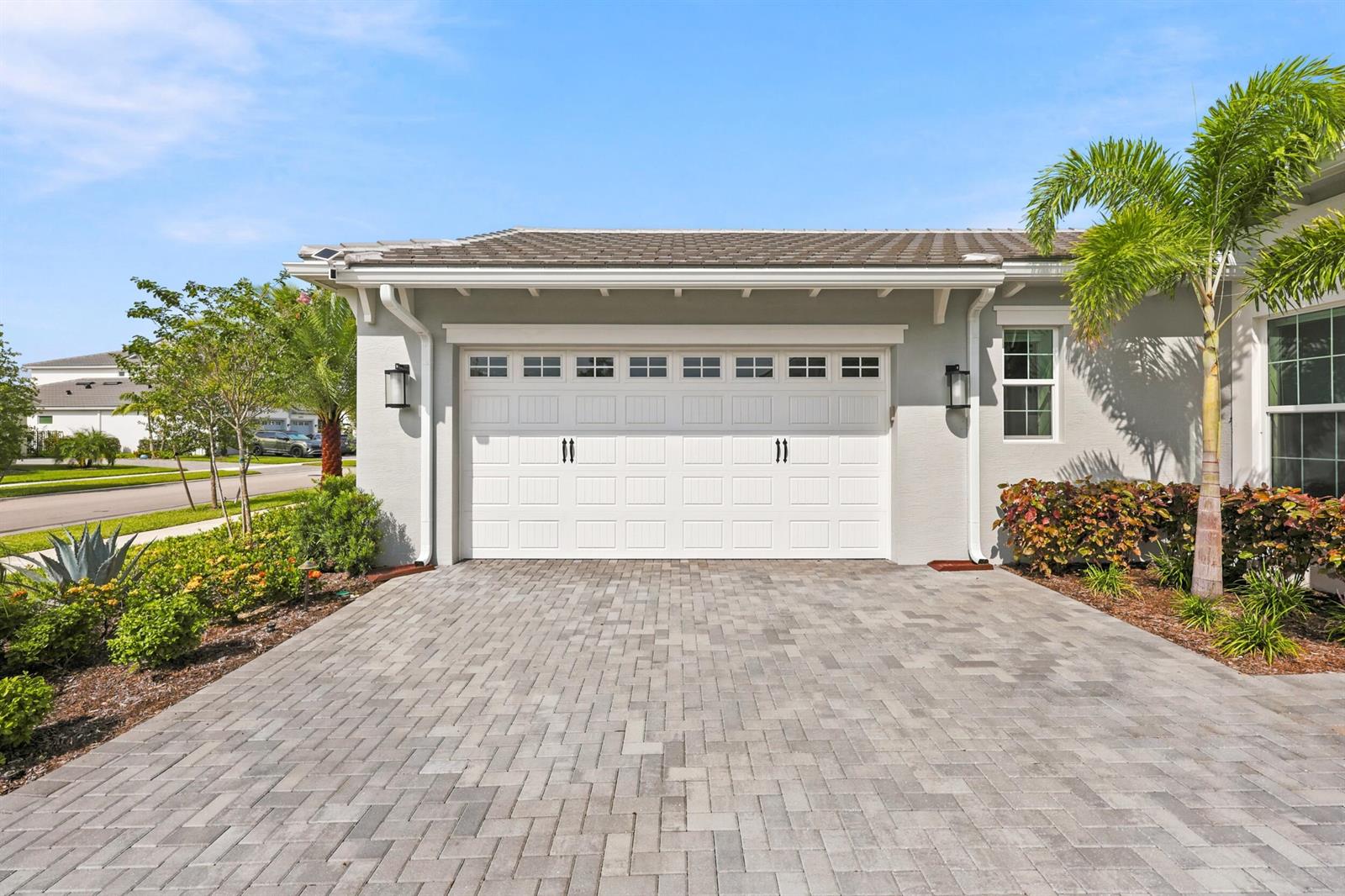 A gray house exterior features a two-car garage with a paver driveway and palm tree — 14831 Wildwood Circle, Westlake FL 33470, WESTLAKE, FL