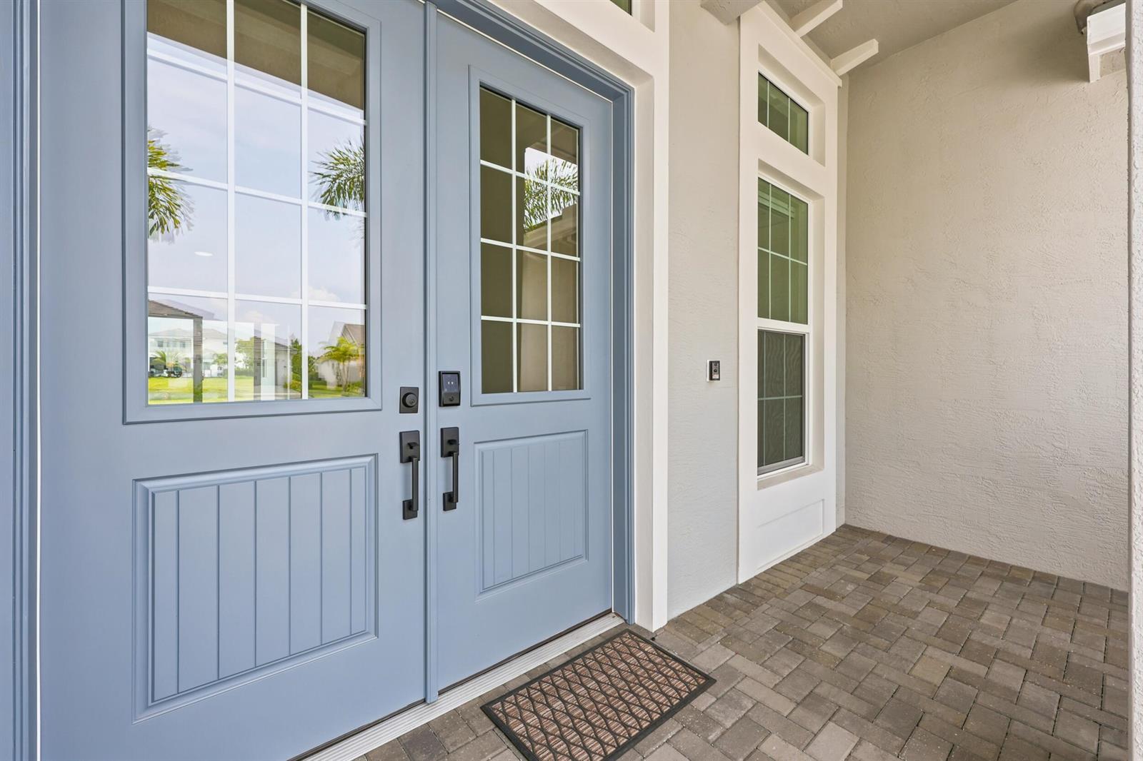 A light blue double front door with glass panels opens onto a paved entryway porch — 14831 Wildwood Circle, Westlake FL 33470, WESTLAKE, FL