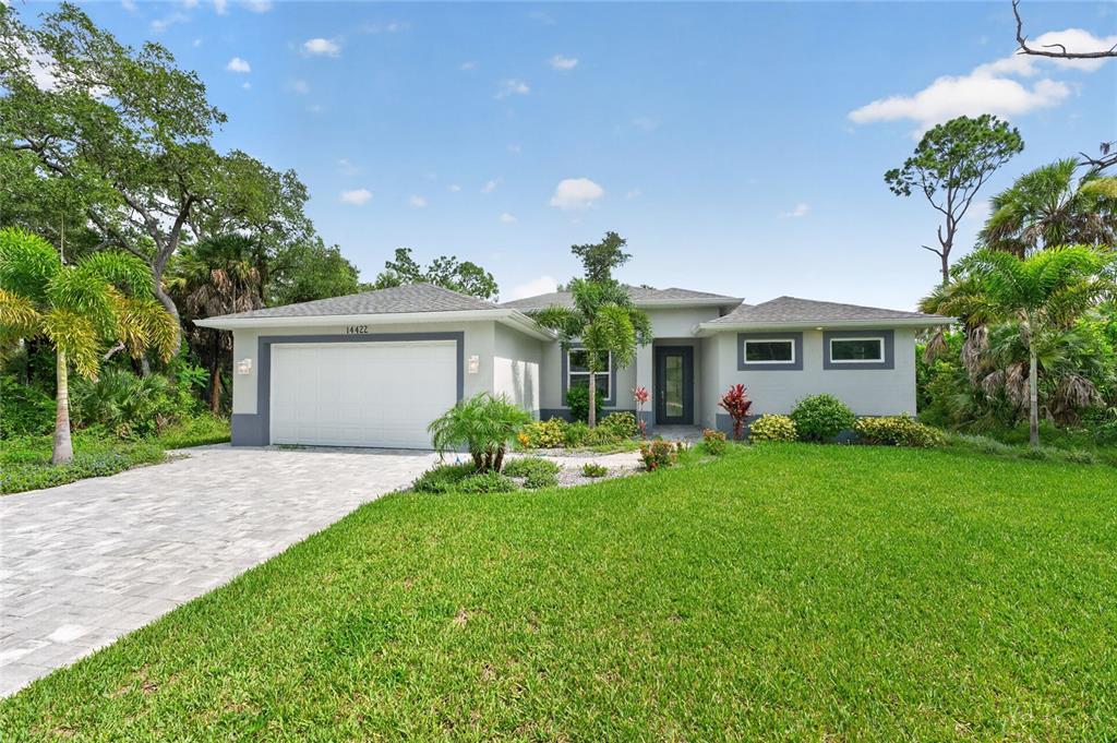 A single-story house with a white garage, gray exterior, and a paved driveway — 14422 CHAMBERLAIN BOULEVARD, PORT CHARLOTTE, FL