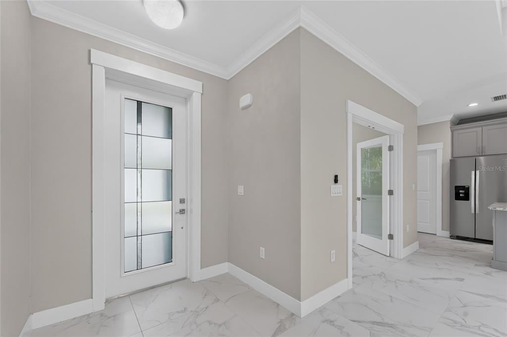 An entryway with white tile floors, a glass-paneled front door, and a doorway leading inside — 14422 CHAMBERLAIN BOULEVARD, PORT CHARLOTTE, FL