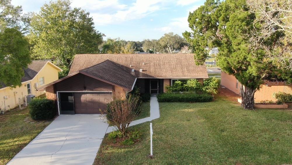 An aerial view of a single-story house with a brown roof, garage, and front lawn — 1350 GLENGARRY DRIVE, PALM HARBOR, FL