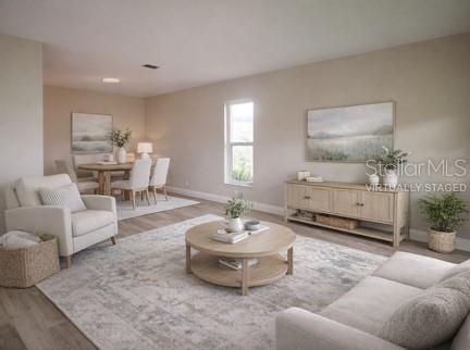 This is a virtually staged living and dining room with neutral walls and light wood furniture — 1350 GLENGARRY DRIVE, PALM HARBOR, FL