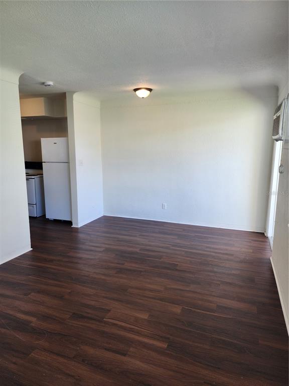 An empty room with dark wood-look flooring, white walls, and a view into a kitchen — 2227 HIGHLAND STREET UNIT 2, ST PETERSBURG, FL