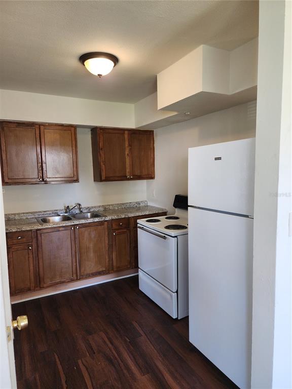 A kitchen features wood cabinets, granite-look countertops, white appliances, and dark wood-look flooring — 2227 HIGHLAND STREET UNIT 2, ST PETERSBURG, FL