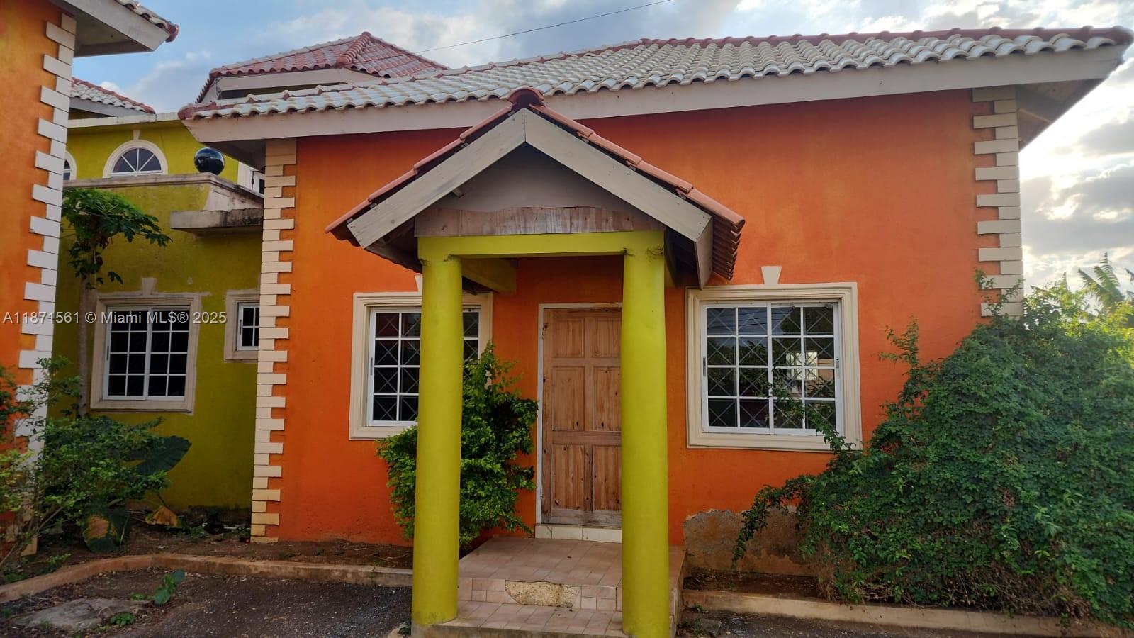 An orange house with a tiled roof, a covered porch, and two yellow support columns — 00 WILTSHIRE, TRELAWNY # 00, NA, NA