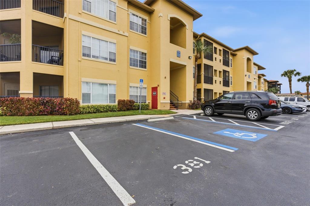 A multi-story apartment building exterior features a parking lot with a designated handicap space — 4345 BAYSIDE VILLAGE DRIVE UNIT 302, TAMPA, FL
