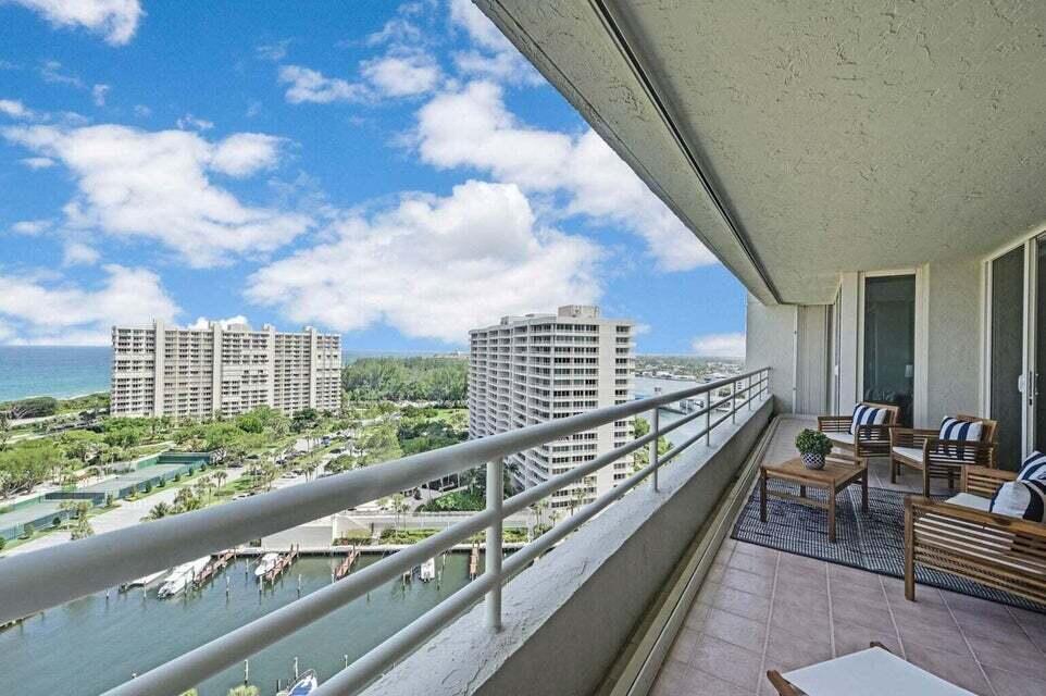 A balcony with outdoor furniture overlooks a waterway, green space, and high-rise buildings — 4201 N Ocean Boulevard # 1605, Boca Raton FL 33431, BOCA RATON, FL