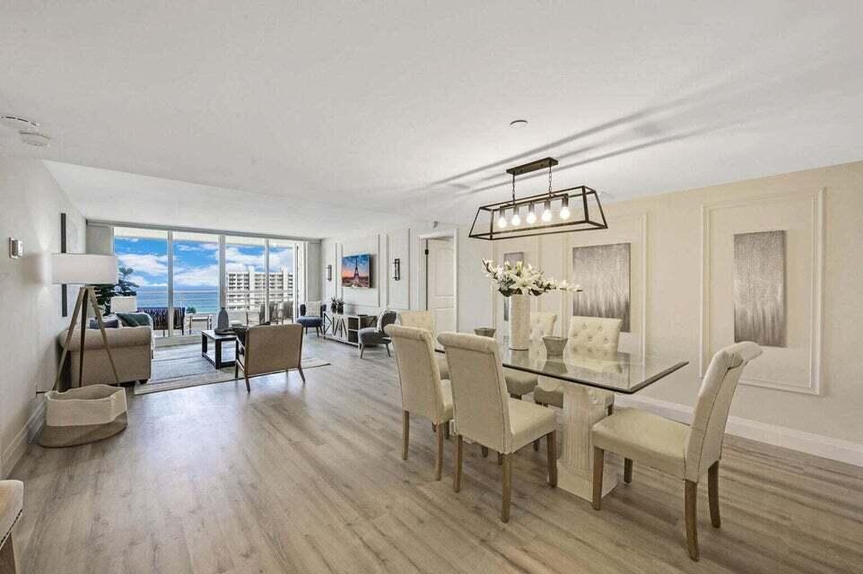 An open-concept living and dining area features light wood flooring, a glass-topped table, and balcony views — 4201 N Ocean Boulevard # 1605, Boca Raton FL 33431, BOCA RATON, FL