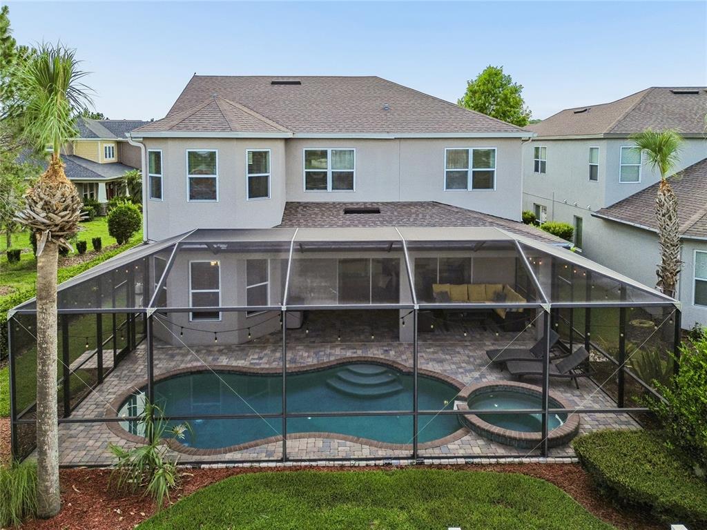 An aerial view of a two-story house with a screened-in pool and hot tub — 9323 BELLA VITA CIRCLE, LAND O LAKES, FL