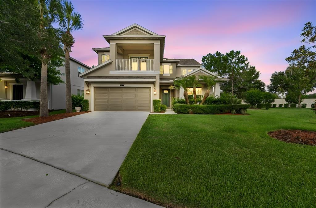 A two-story suburban house with a concrete driveway, a garage, and a second-floor balcony — 9323 BELLA VITA CIRCLE, LAND O LAKES, FL